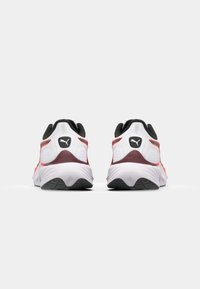 Weiße Sportschuhe mit schwarzen Akzenten, ausgestattet mit einer gepolsterten Sohle, einem strukturierten hinteren Bereich und orangefarbenen Details an den Seiten.
