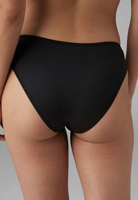 Crne visokotoplje gaćice izrađene od mekog materijala. Imaju glatku teksturu, elastičnu traku u struku i minimalne detalje šivanja.