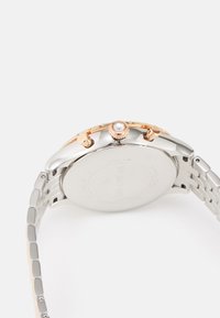 Orologio argento con bracciale in metallo bicolore, dotato di una corona in oro rosa, di un accento in cristallo trasparente e di una cassa in acciaio inossidabile lucido.