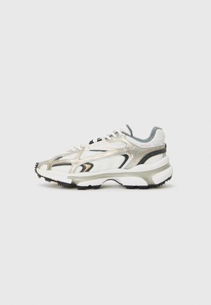 Chunky sneaker in wit, grijs en metallic zilver met textureerde panelen. Heeft een dikke zwarte rubberen zool en een opvallend overlay-ontwerp.