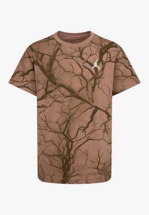 T-shirt marron à manches courtes avec un motif sombre de branches d'arbre et un petit logo Jumpman blanc sur la partie supérieure gauche de la poitrine.