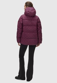 Dunjacka med huva, tillverkad av kviltat tyg i rosa och svart geometriskt mönster. Har en boxig design och långa ärmar.