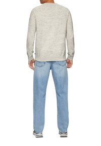 Lichtgrijs gespikkeld sweater met lange mouwen, ronde halslijn, gecombineerd met lichtblauwe denim jeans en zwart-witte sneakers.