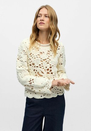 Strickpullover in Creme mit floralen Ausschnitten und Glockenärmeln. Das strukturierten Design weist durchgehende Durchbrüche im gesamten Kleidungsstück auf.