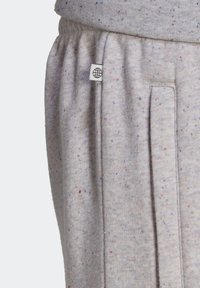 Ljust grå spräckliga svettbyxor med resår i midjan och en liten vit tygetikett med en svart globikon.