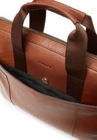 Brun läderhandväska med texturerad yta, dubbla tyghandtag, dragkedjestängning och ett mönstrat innerfoder med magnetknapp.