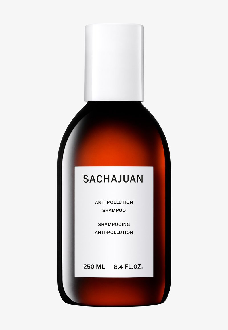 Bouteille en verre brun avec un capuchon blanc. L'étiquette affiche "SACHAJUAN", "SHAMPOOING ANTI-POLLUTION", ainsi que des mesures en millilitres et en onces liquides.