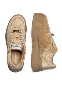 Sneaker beige in materiale scamosciato testurizzato, con suola rialzata, punta forata e dettaglio di marca sulla linguetta.
