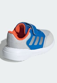 Szary sportowy but z siateczki z niebieskimi i pomarańczowymi akcentami, regulowanym paskiem i białą gumową podeszwą. Posiada trzy odblaskowe paski po bokach.