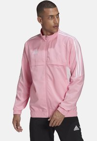 Pinker Zip-Jacke mit weißen Akzenten, ausgestattet mit einem Stehkragen, elastischen Bündchen und drei weißen Streifen an jedem Ärmel.