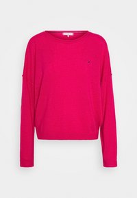 Pull en maille fuchsia à manches longues, col rond et petit détail de logo. Texture douce et coupe décontractée.