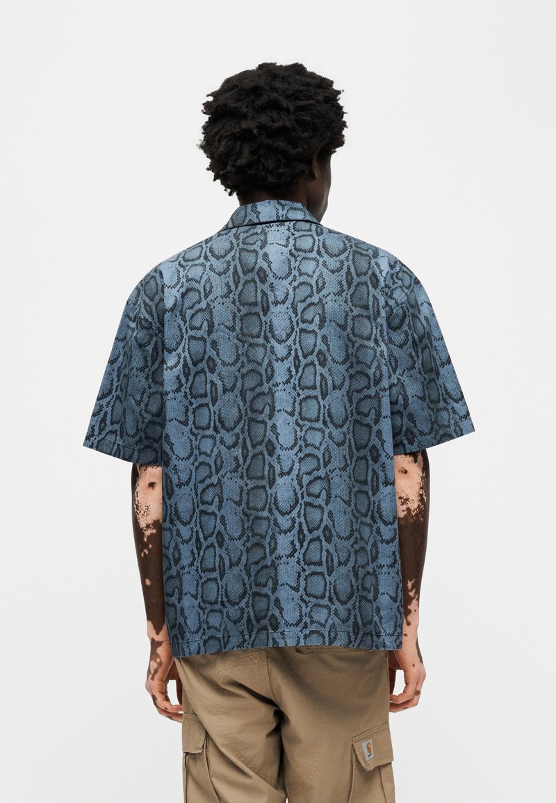 Camisa de manga corta con un patrón de serpiente en azul y negro. Confeccionada con una tela ligera, corte recto y cuello clásico.