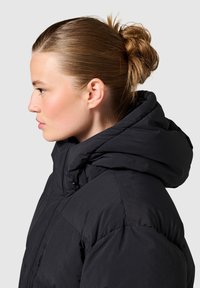 Sort pufferjakke med høj krave og justerbar hætte. Glat tekstur og polstret design; har lynlåslukning og minimalistiske hardware-detaljer.