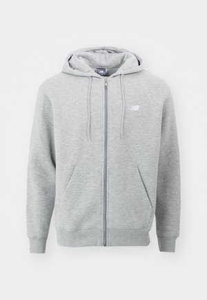 Sweat à capuche zippé New Balance gris clair avec cordons, poches avant et logo sur la poitrine gauche sur fond blanc.