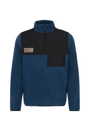 Pullover in pile di colore blu scuro con un pannello nero e colletto con zip, dotato di tasca sul petto e un'etichetta con "DEDICATO ALLA PERFEZIONE."