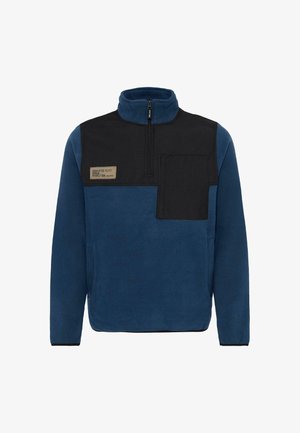Fleece-pullover i mørkeblå med en sort panel og glidelås krage, med en brystlomme og en etikett med "DEDICERT TIL PERFEKSJON."