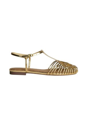Sandalia plana dorada con diseño de puntera en jaula tejida, tira en el tobillo con hebilla y suela baja marrón.
