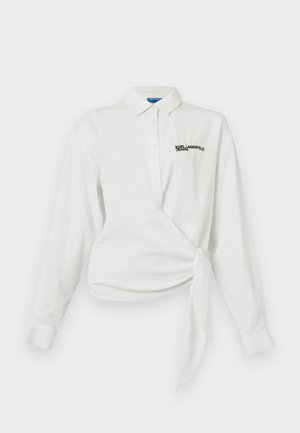 Bijela košulja dugih rukava s omotanim dizajnom, gumbima, oštrim ovratnikom i izvezenom crnom logotipom na prsima. Glatka pamučna tekstura.