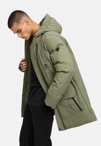 Zelená oteplená parka s kapucňou, s vreckami na zips a gombíky, textúrovaný materiál a mierne voľný strih.