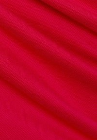 Heldere roze stof met een gestructureerd breipatroon. Het oppervlak is glad, met zachte plooien en draperingen. Geschikt voor kleding of bekleding.