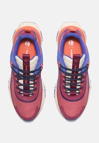 Lila und pinke Textilsneaker mit gepolsteter Sohle, gemusterten Schnürsenkeln und orangefarbenen Akzenten. Mit einer Zuglasche an der Ferse.