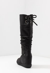 Botte noire montante en cuir souple avec un design froissé, un détail à lacets en haut et un talon compensé pour une élévation supplémentaire.