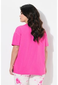 Camiseta de manga corta en rosa intenso con un corte relajado y un cuello redondo. Textura suave, con un diseño liso y una parte trasera ligeramente más larga.