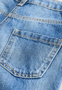 Jeans-Shorts in hellblau mit einer gesteppten Gesäßtasche und kontrastierenden gelben Nähtelementen. Weicher Stoff und lässiges Design.
