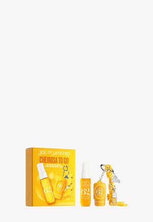 Spray, baume et porte-clés Sol De Janeiro Cheirosa to Go avec un emballage jaune et un charme argenté, tous présentés sur un fond blanc.