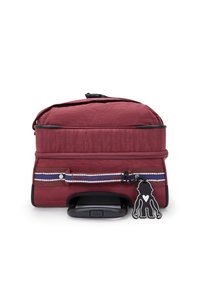 Red fabric travel bag with a top handle, accented with a striped strap, and a black charm attached. Features a zipper closure and sturdy base.