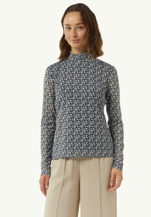 Langsleeve top met een geometrisch patroon in marineblauw en crème, hoge halslijn en een aansluitend design. Materiaal lijkt glad en rekbaar.