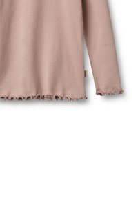 Ribbed pitkähihaine toppi pehmeän vaaleanpunaisen sävyssä, frayed-helmalla ja -hihoilla. Pinta on teksturoitua ja malli on rento.