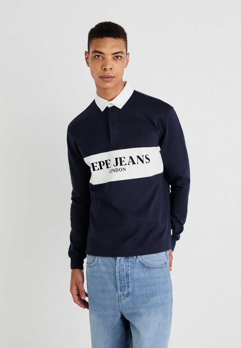 Polo de manga larga en color navy con cuello blanco y banda central, que presenta 'PEPE JEANS LONDON' en texto negro en negrita. Tela texturizada.