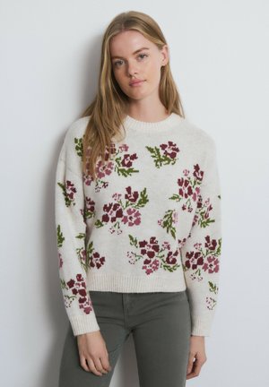 Knit sweater in cream with floral patterns in dark red and green. Crew neck, long sleeves, ribbed hem, and textured fabric.