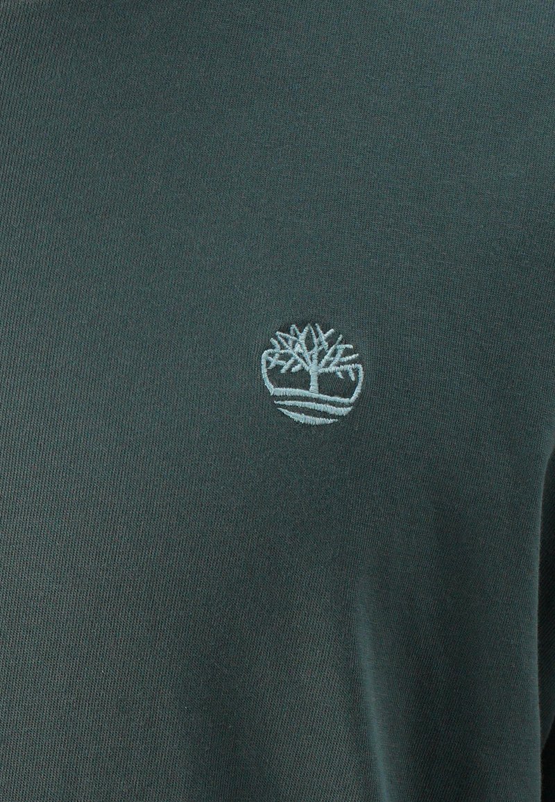Sudadera verde oscuro con un logo de árbol bordado en azul claro en el pecho, hecha de un suave material de algodón texturizado.