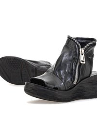 Czarne skórzane botki na obcasie z odkrytą palcą, z zamkiem błyskawicznym, teksturowaną czarną podeszwą platformową i gładkim wykończeniem. Zauważalny detal w postaci ozdobnego zamka.