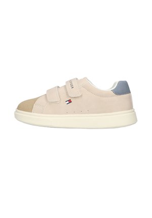 Baskets beiges avec deux bandes velcro, bout en suède marron, patch bleu au talon et petit logo drapeau sur le côté avec semelle blanche.