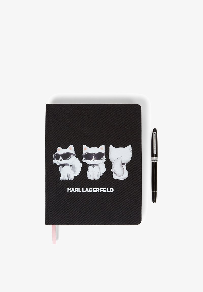 Carnet noir avec trois chats blancs portant des lunettes de soleil imprimés sur la couverture et un stylo noir placé à côté.