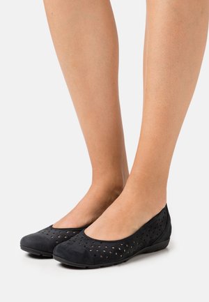Ballerines noires en daim avec un motif de trous perforés, bout rond et semelle flexible. Texture lisse avec un design à découpe basse.