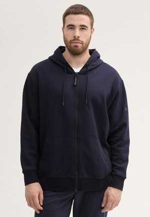Marineblauwe zip-up hoodie van gladde stof, met een capuchon met trekkoord, voorzakken en ribbelboorden. Eenvoudig, praktisch ontwerp.