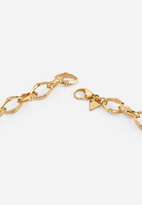 Gold chain necklace featuring interlocking links, adorned with small crystals, and a clasp with a branded triangular tag.