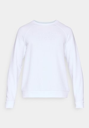 Bela majica s kapuco in raglan rokavi, z rebrastimi manšetami in okroglo ovratnikom. Na sprednji strani je izbočen napis "TED BAKER SPORT". Gladka tekstura.