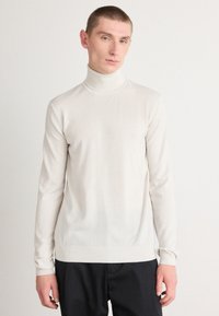 Helebeež turtleneck-sviiter, mis on valmistatud siledast kudumisest, millel on pika varrukaga ja slim-fit disain, millel on soonikkoes mansetid ja hem.