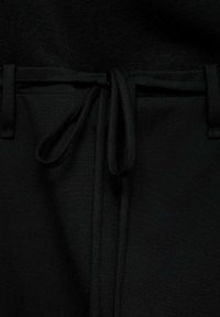 Schwarze Hose mit glatter Textur, ausgestattet mit einem Kordelzugbund und Gürtelschlaufen. Einfache Gestaltung, minimalistische Details für Vielseitigkeit.