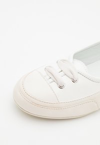 Baskets en cuir blanc avec un bout rond, semelle en caoutchouc crème texturé et lacets beige. Comprend des œillets en métal et des détails de couture.