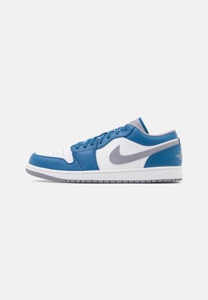 Baskets basses Nike bleu, blanc et gris avec logo swoosh gris et zone des orteils perforée, vues de côté sur un fond uni.