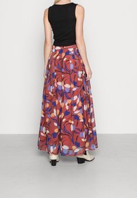 Maxi hame, jossa on kukkakuosi, sisältäen punaisia, sinisiä ja valkoisia sävyjä. Valmistettu kevyestä kankaasta, jossa on ilmava muotoilu ja korkea vyötärö.