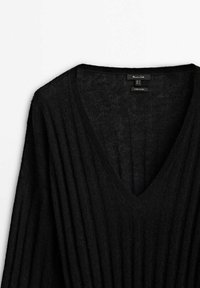 Pull noir en maille côtelée avec col en V, manches longues, texture douce et étiquette de taille à l'intérieur du col.