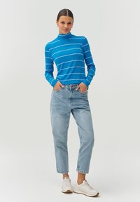 Zils svītrainā turtlenecks ar garām piedurknēm, apvienots ar gaiši ziliem augstās jostasvietas džinsiem un baltām kedām. Vienkāršs dizains un brīvs piegriezums.