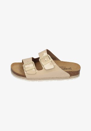 Beige slip-on sandal with two adjustable buckles, cork footbed, and textured rubber sole. Smooth upper material with a glossy finish.